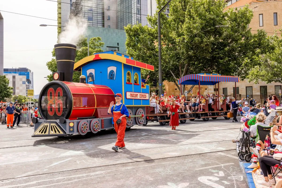 A train traveling along a street, surrounded by buildings and trees, showcasing urban transportation.