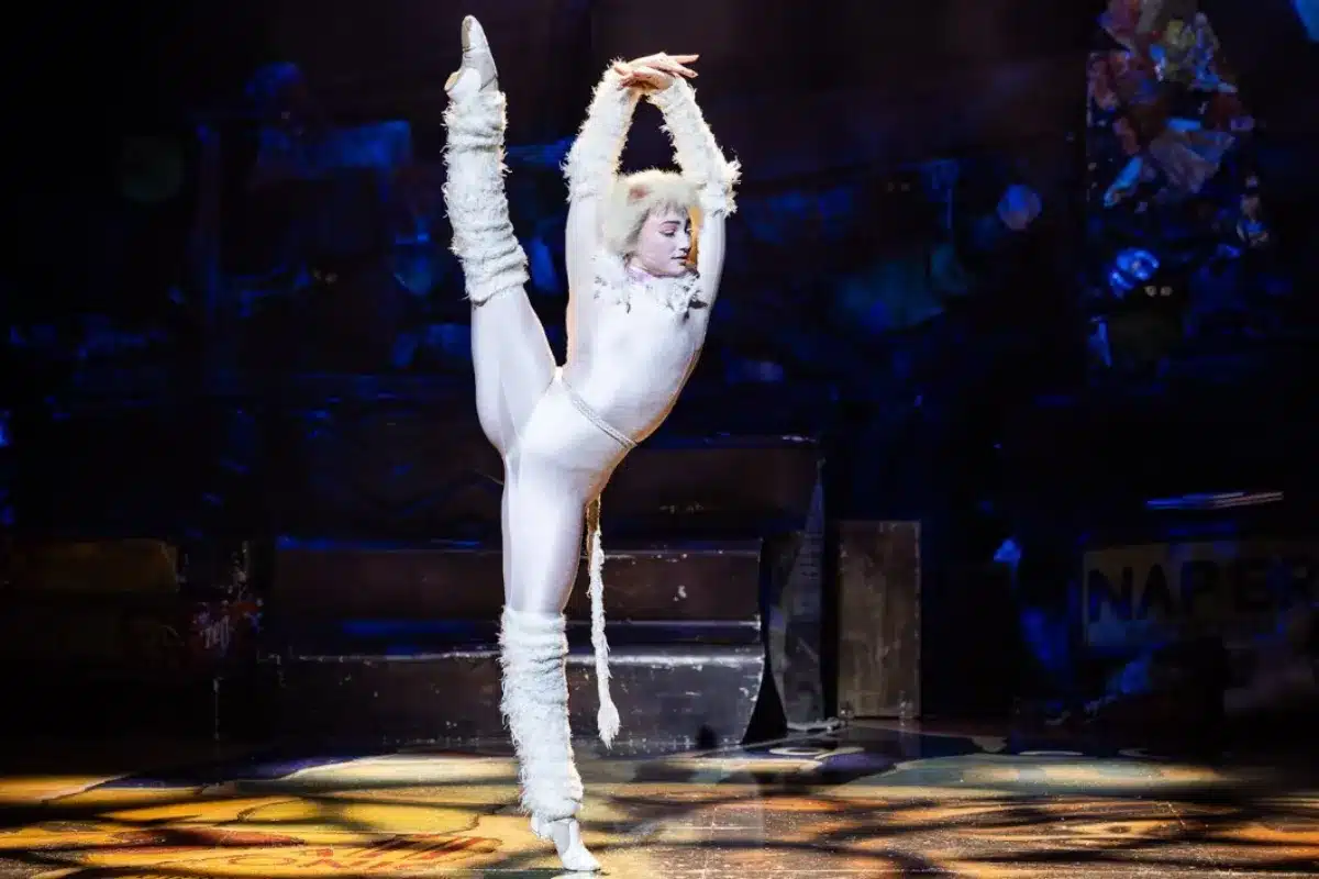 A woman in a white outfit performs on stage, captivating the audience with her presence and energy.