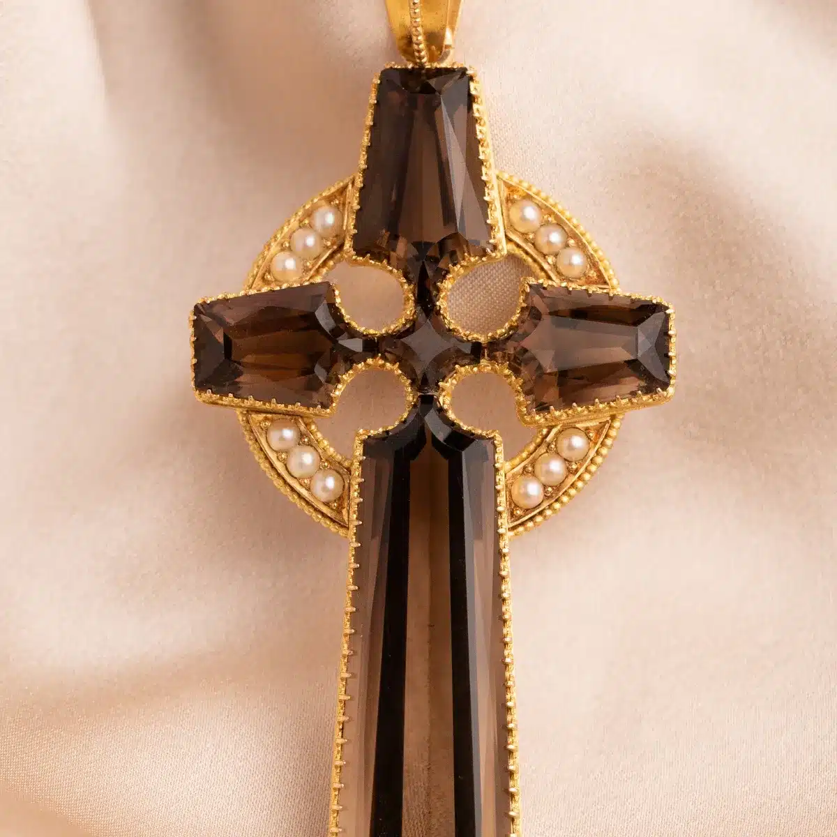 A gold cross pendant featuring a brown crystal stone at its center, elegantly designed for a classic look.