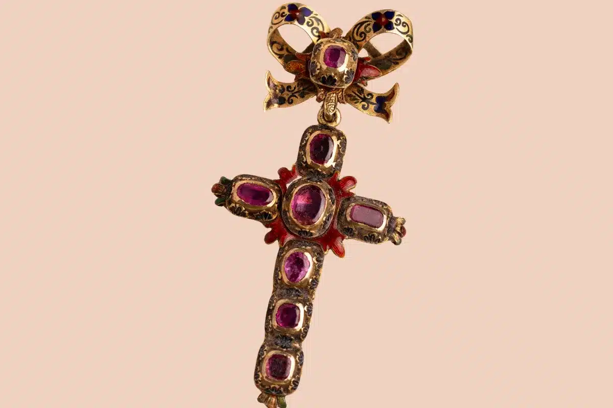 A decorative cross featuring a pink stone centerpiece with elegant gold accents.