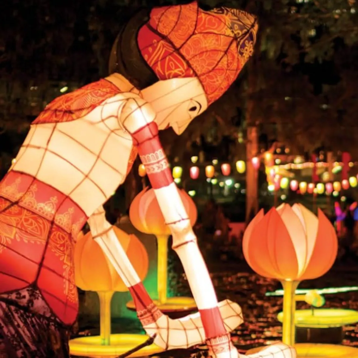 A man in a costume holds a lantern, illuminating his surroundings with a warm glow.