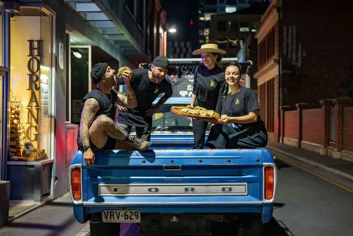 People sitting together on the back of a truck, enjoying a casual moment outdoors.