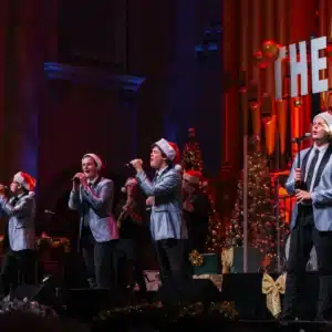 A group of men performing a song together on stage, engaging the audience with their vocal harmony and energy.