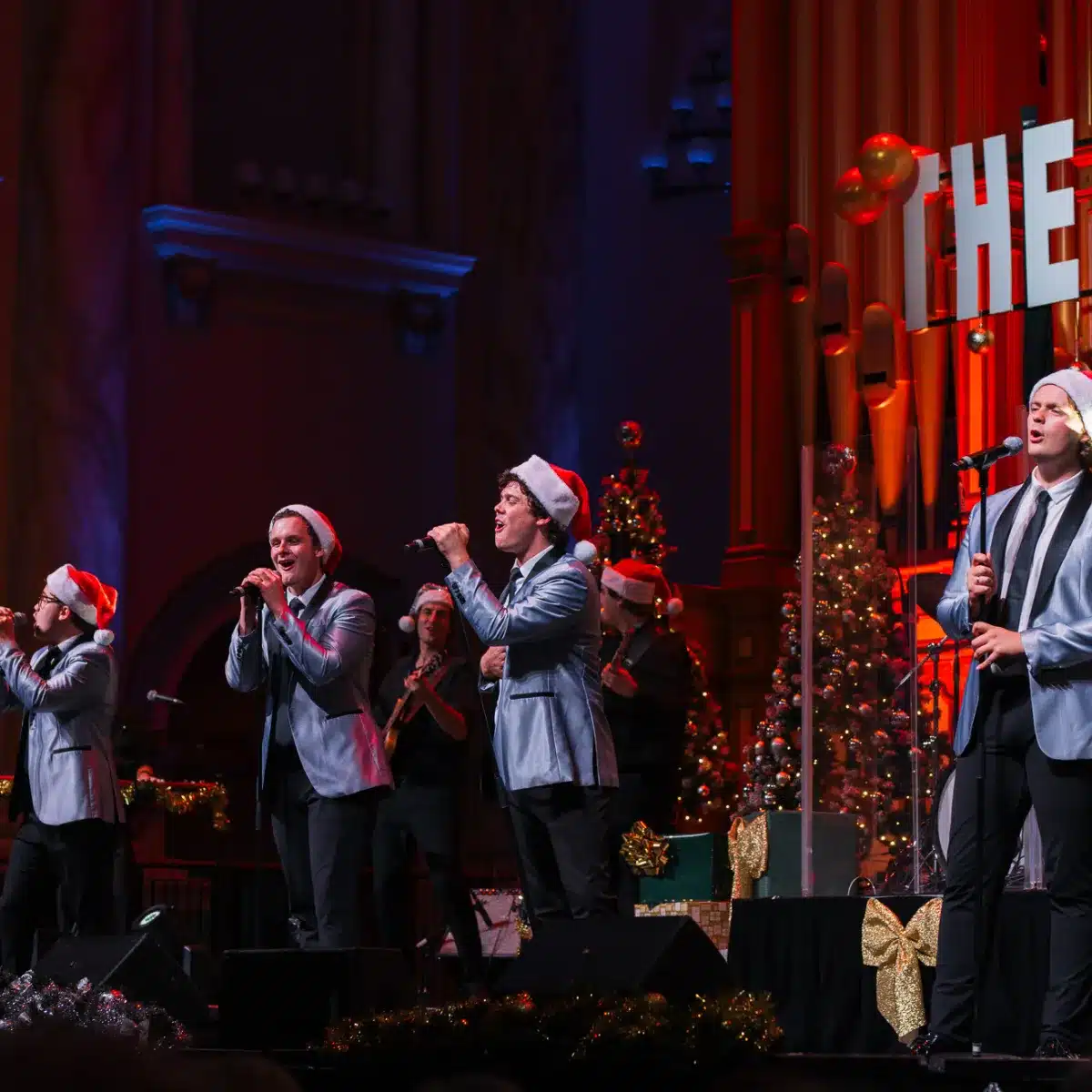 A group of men performing a song together on stage, engaging the audience with their vocal harmony and energy.