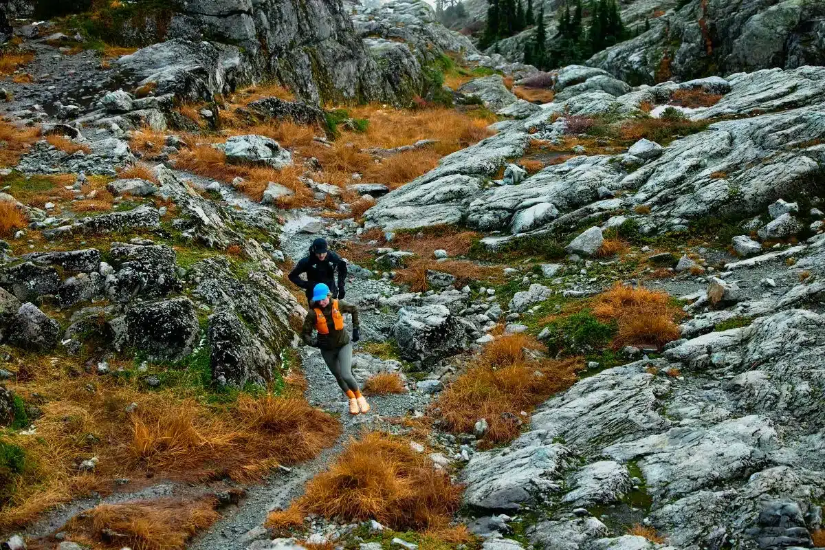 A woman with a backpack stands on a mountain, enjoying the scenic view around her.