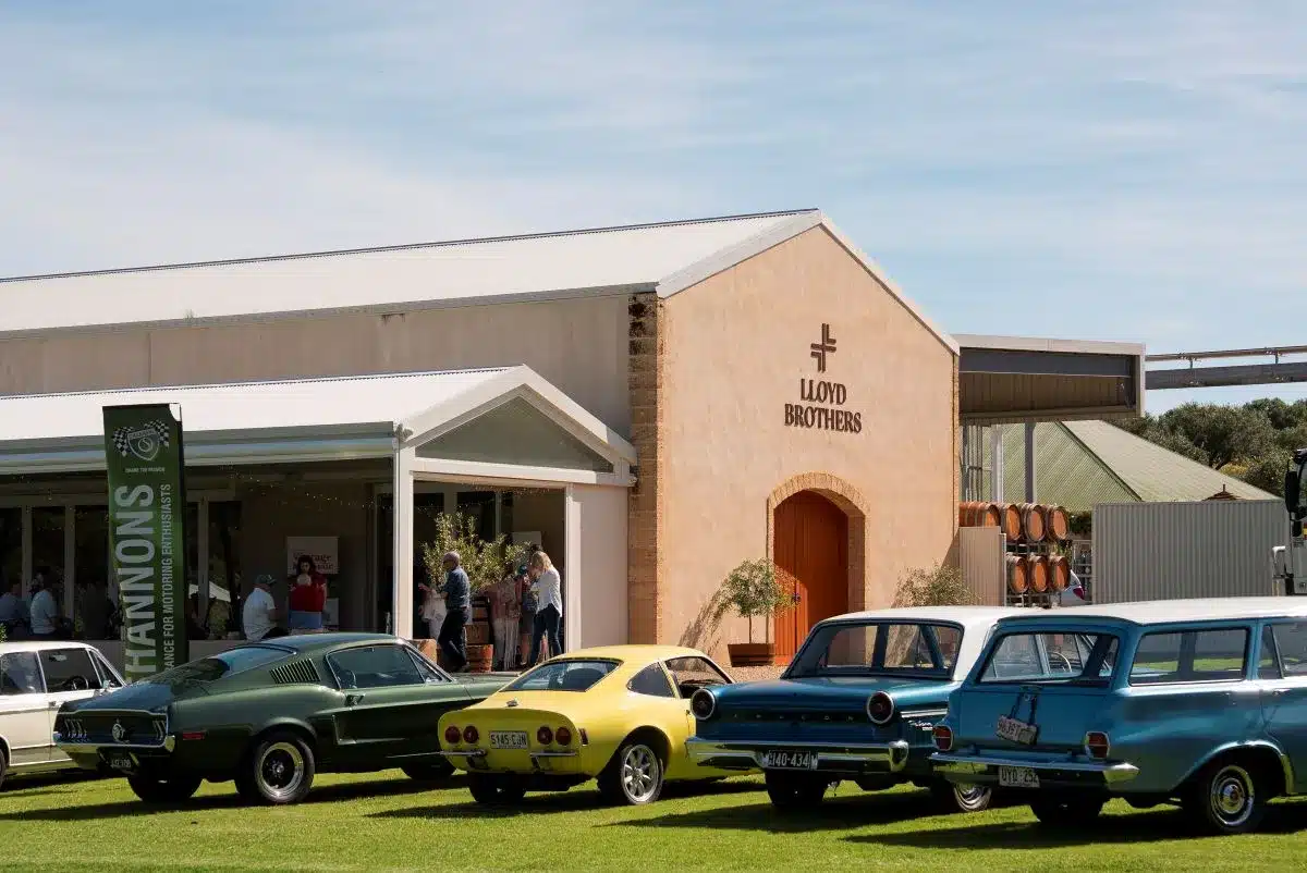 A lineup of classic cars parked in front of a building, showcasing their vintage designs and colors.