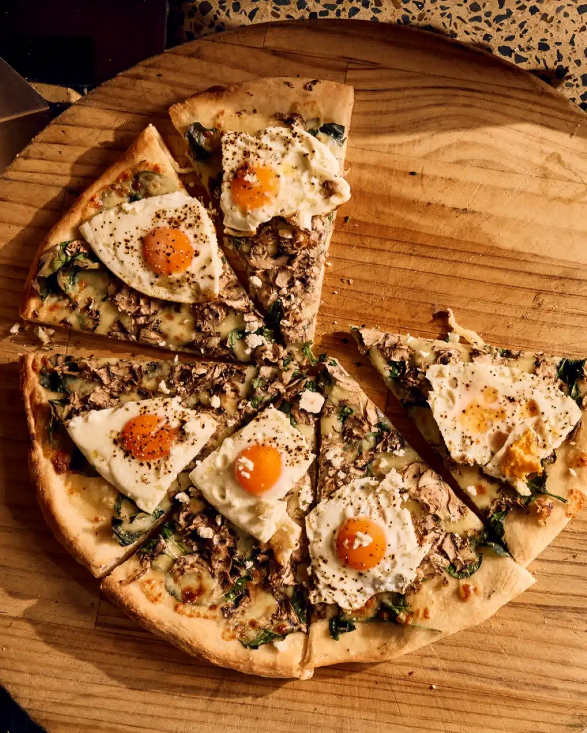 A pizza topped with an egg sits on a wooden board.