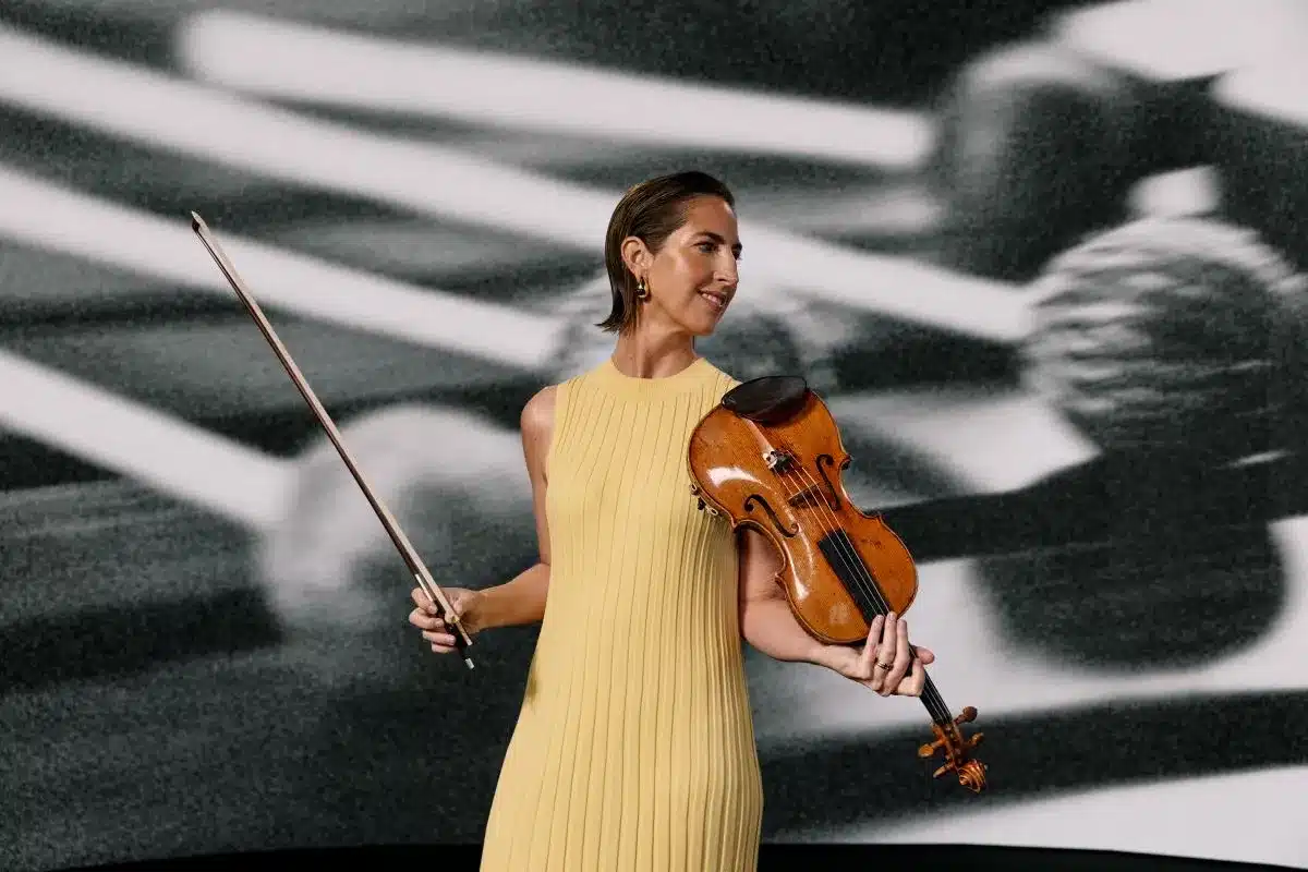 A woman in a yellow dress holds a violin