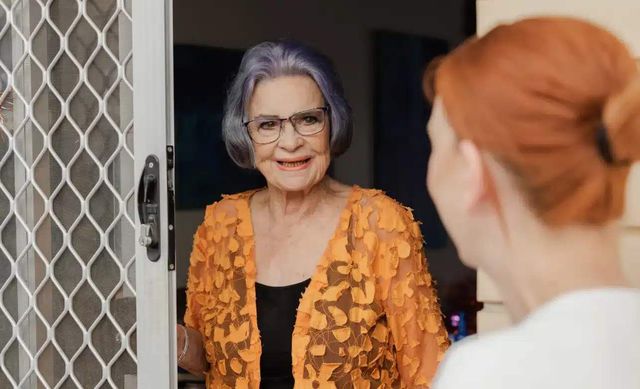 An older woman engages in conversation with a younger woman, both smiling and appearing attentive to each other.