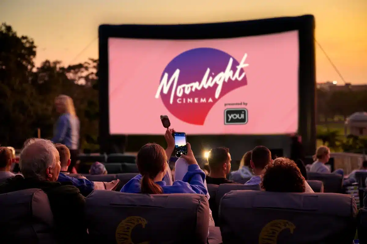 People sitting in chairs, watching a movie on a large screen in a darkened room.