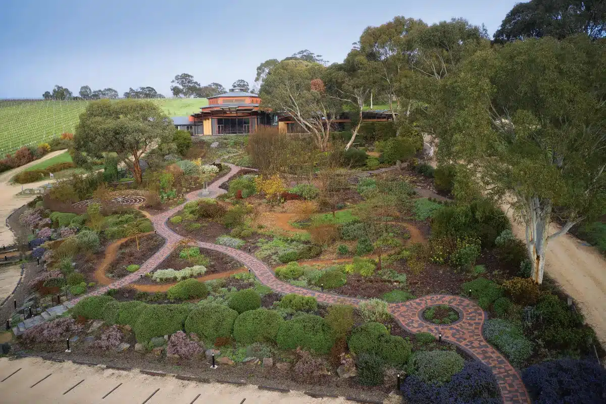 Aerial view of a lush garden with a winding path leading through vibrant flowers and greenery.