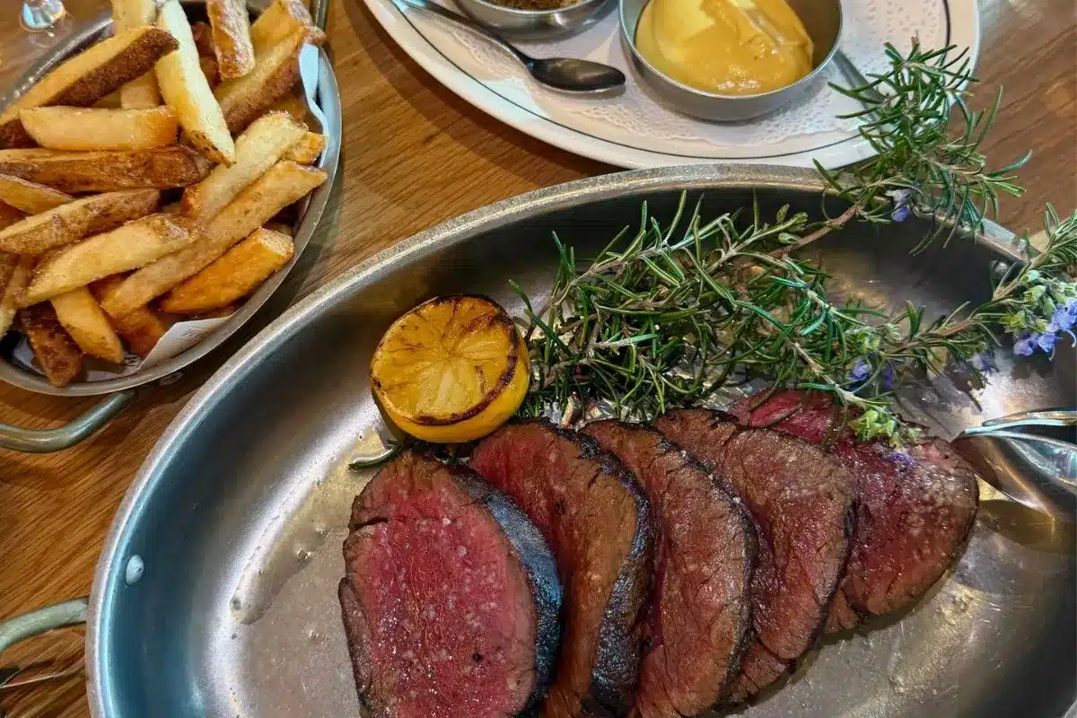 A beautifully arranged steak and fries on a table, paired with a glass of wine, suggesting a fine dining experience.