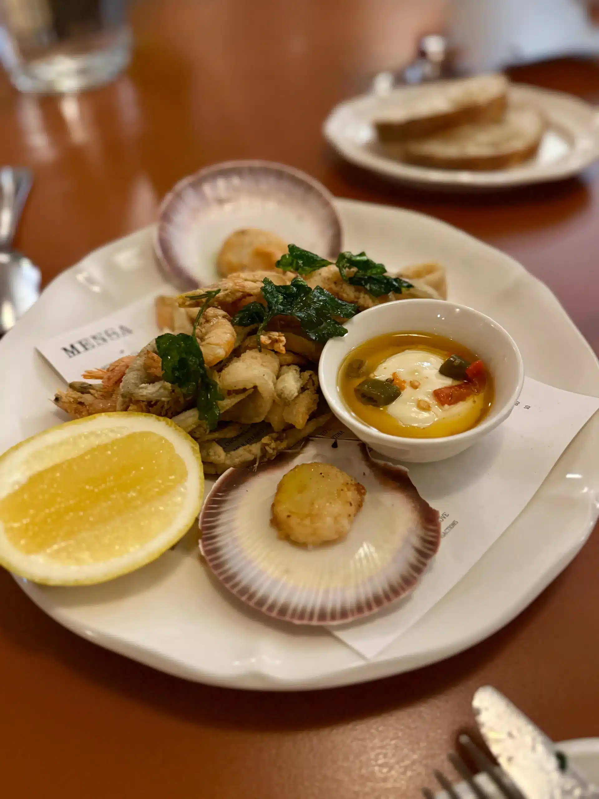 A small plate of Italian-inspired snacks including marinated olives, toasted bread and a dipping sauce.