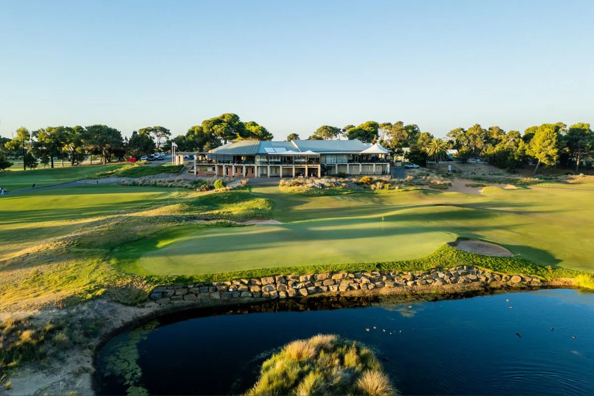 A panoramic view of a golf course, showcasing lush greens and well-maintained fairways under a clear blue sky.