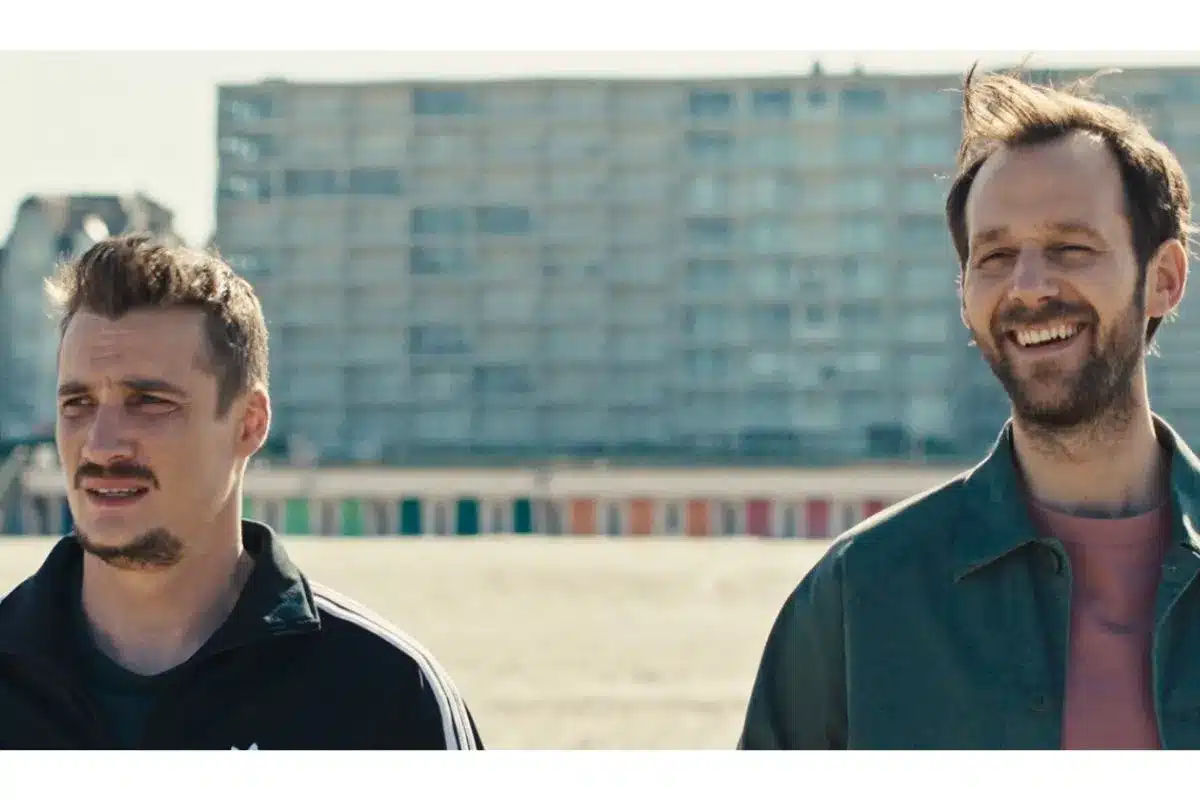 two men walking and smiling in front of a tall building