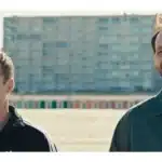 two men walking and smiling in front of a tall building