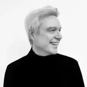 Black and white portrait of musician David Byrne looking out into the distance and smiling