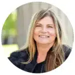 A woman wearing black, sitting in a park and smiling 