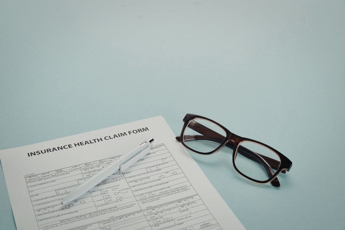 An image of a pair of glasses and pen on an insurance claim form.