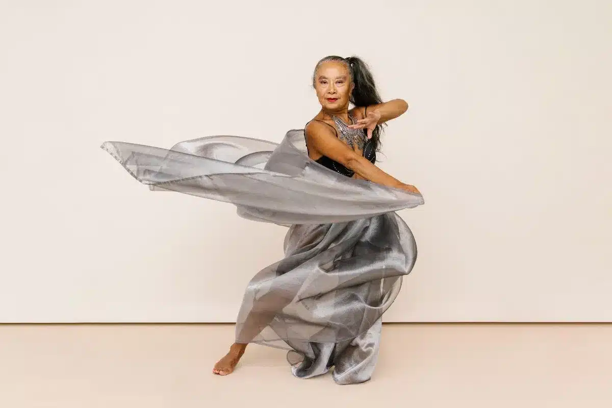 A woman in a shimmering silver dress gracefully dances, showcasing her elegance and joy.