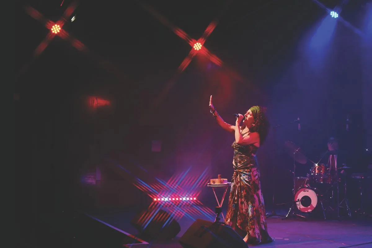 A woman performs in costume to a captivated audience under bright stage lights.