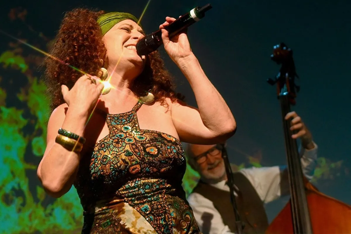 A woman performs in a jazz band singing passionately into a microphone.