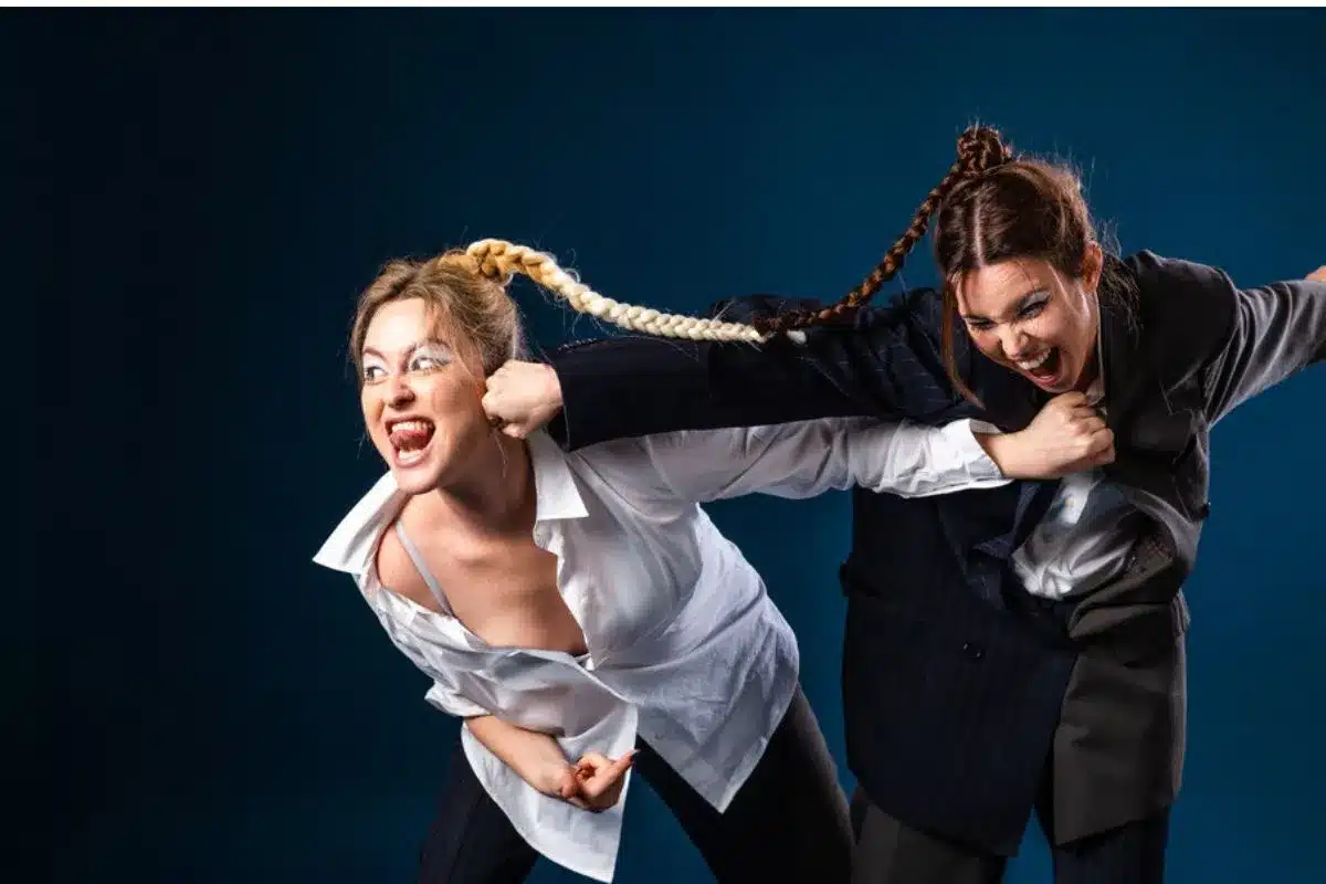 Two women dressed in business suits are fighting, illustrating a dramatic conflict in a professional environment.
