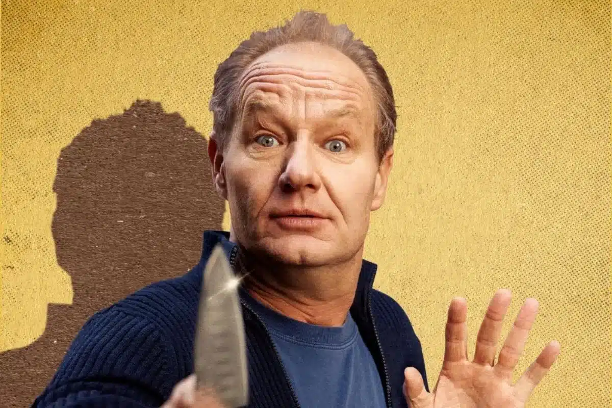 a man yields a knife in front of a yellow wall