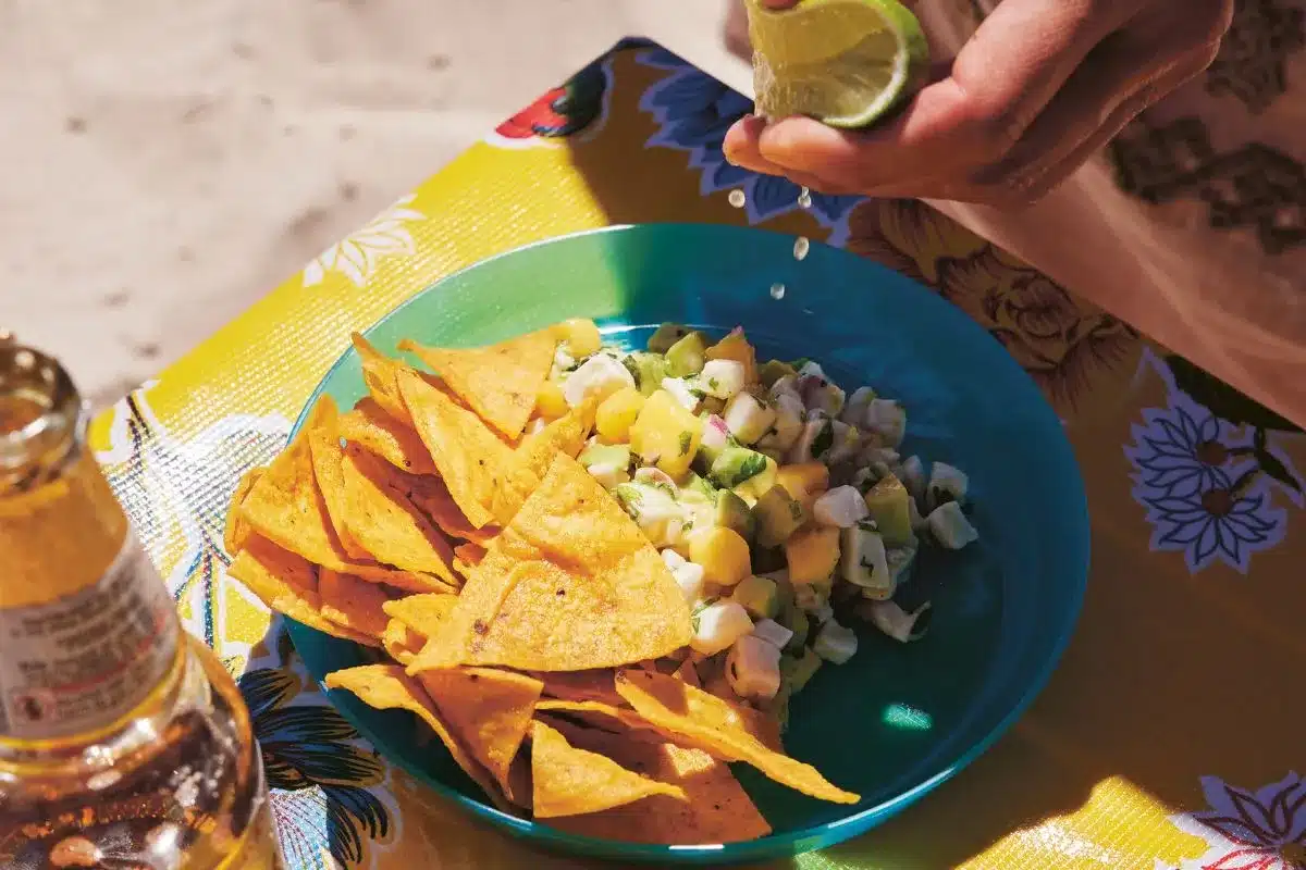 A bowl of ceviche with avocado and mango with corn chips taken from the book iProvecho!