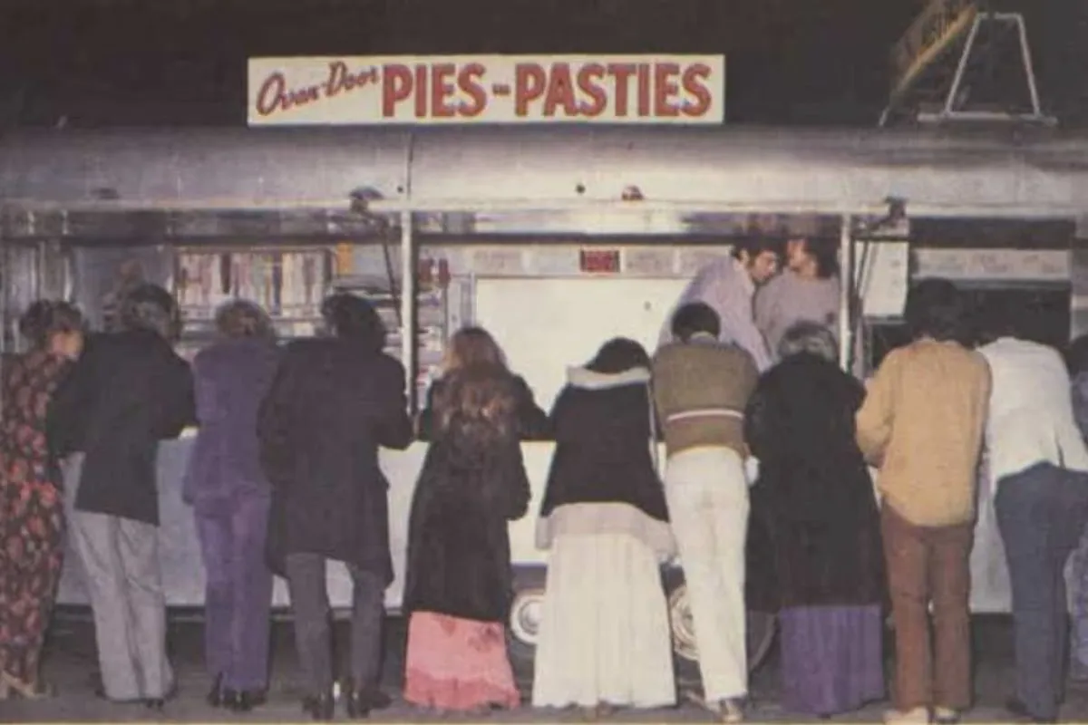 A group of people ordering late night food from a South Australian pie cart.