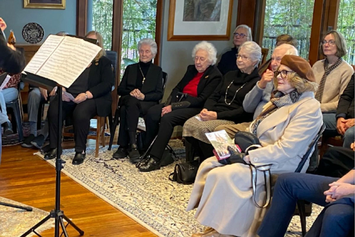 Audience seated in a private home listening to a live chamber music performance during an intimate house concert.