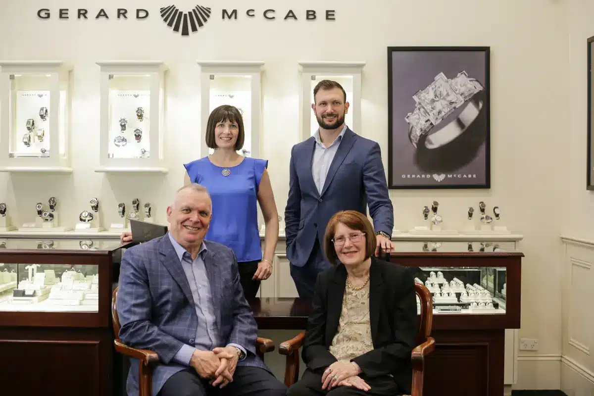 Gerard and Pauline McCabe seated in the foreground with their adult children Jessica and Justin standing behind them, photographed inside the Gerard McCabe store in Adelaide Arcade in 2020, surrounded by jewellery and watch displays.
