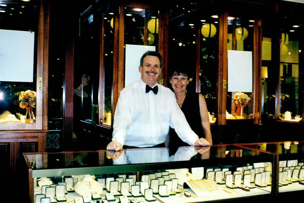 Gerard and Pauline McCabe smiling behind a jewellery display counter filled with diamond and gold pieces at their Excellence in Diamonds Christmas event in 1998.