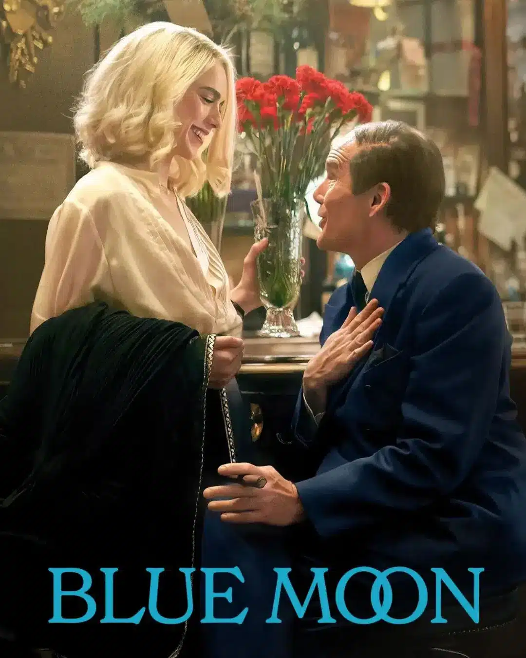 Promotional poster for the film Blue Moon showing a woman with blonde wavy hair laughing with a man in a blue suit at a warmly lit bar, with a vase of red carnations between them. The film title appears in blue text at the bottom.