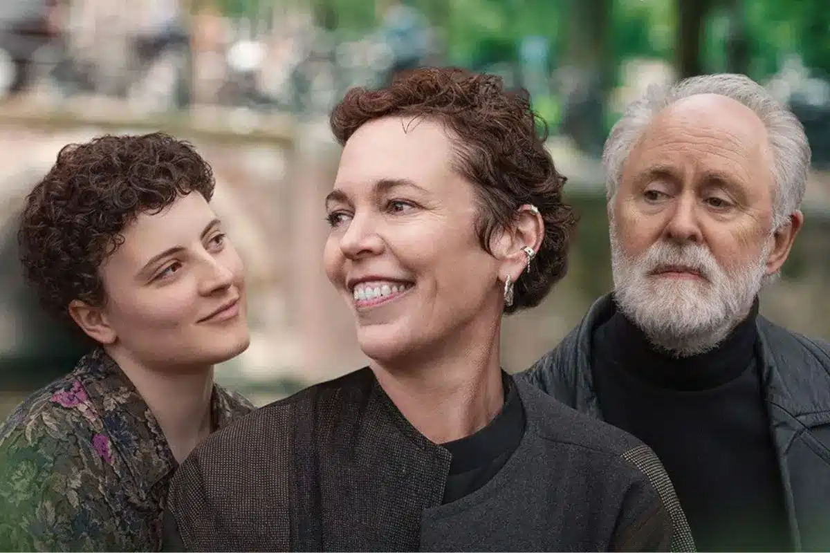 Promotional image for the film Jimpa featuring three characters against a blurred green outdoor backdrop — a young curly-haired woman on the left, a smiling woman with short auburn hair in the centre, and an older bearded man on the right.