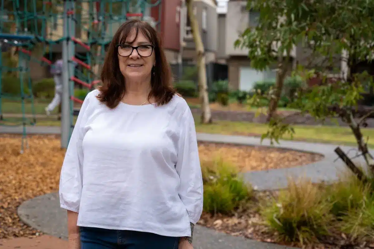 A woman in a white shirt standing in an autumn garden.