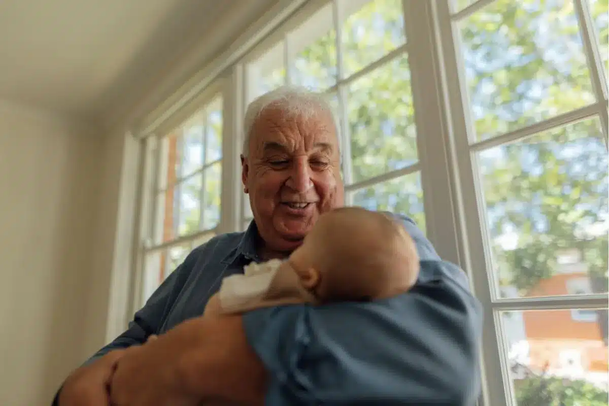 Happy older man holding a baby and enjoying life at an ECH retirement community