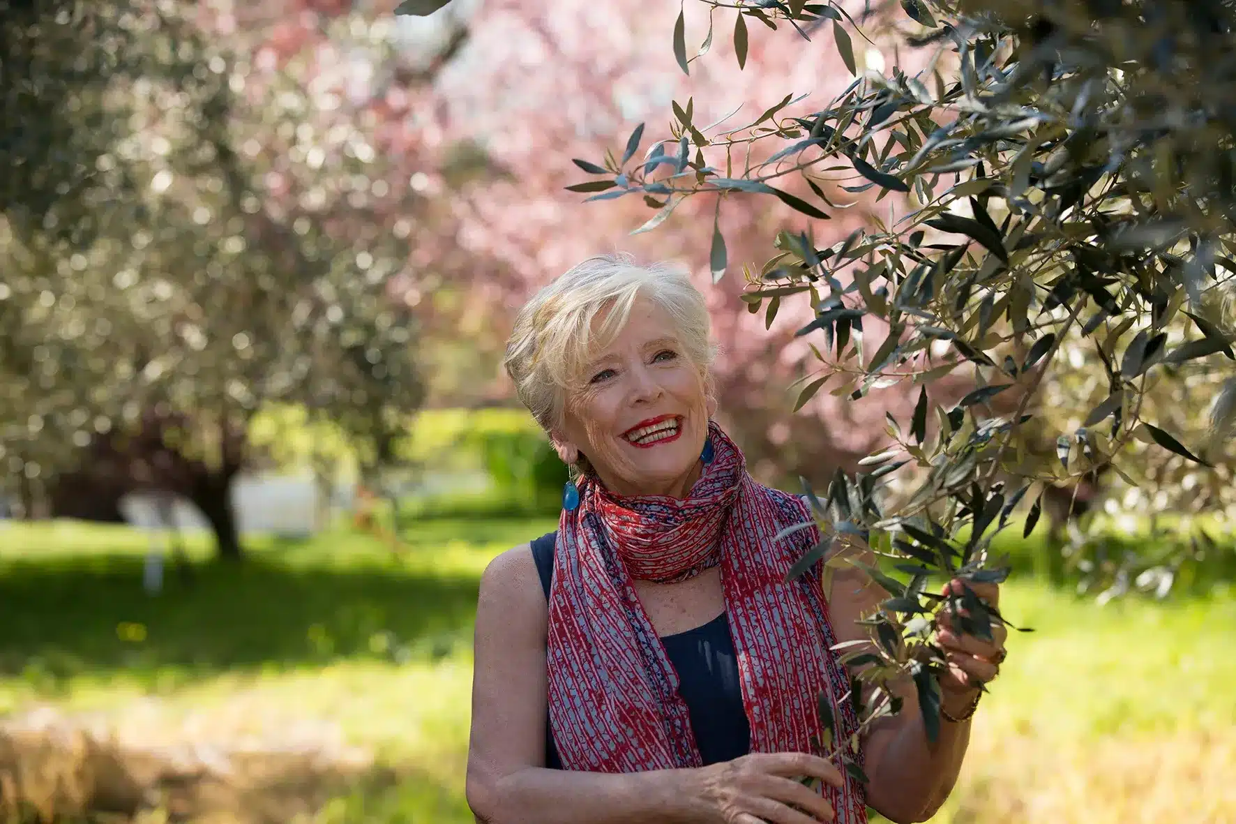 Maggie Beer in a scarf beside a tree on a sunny day.