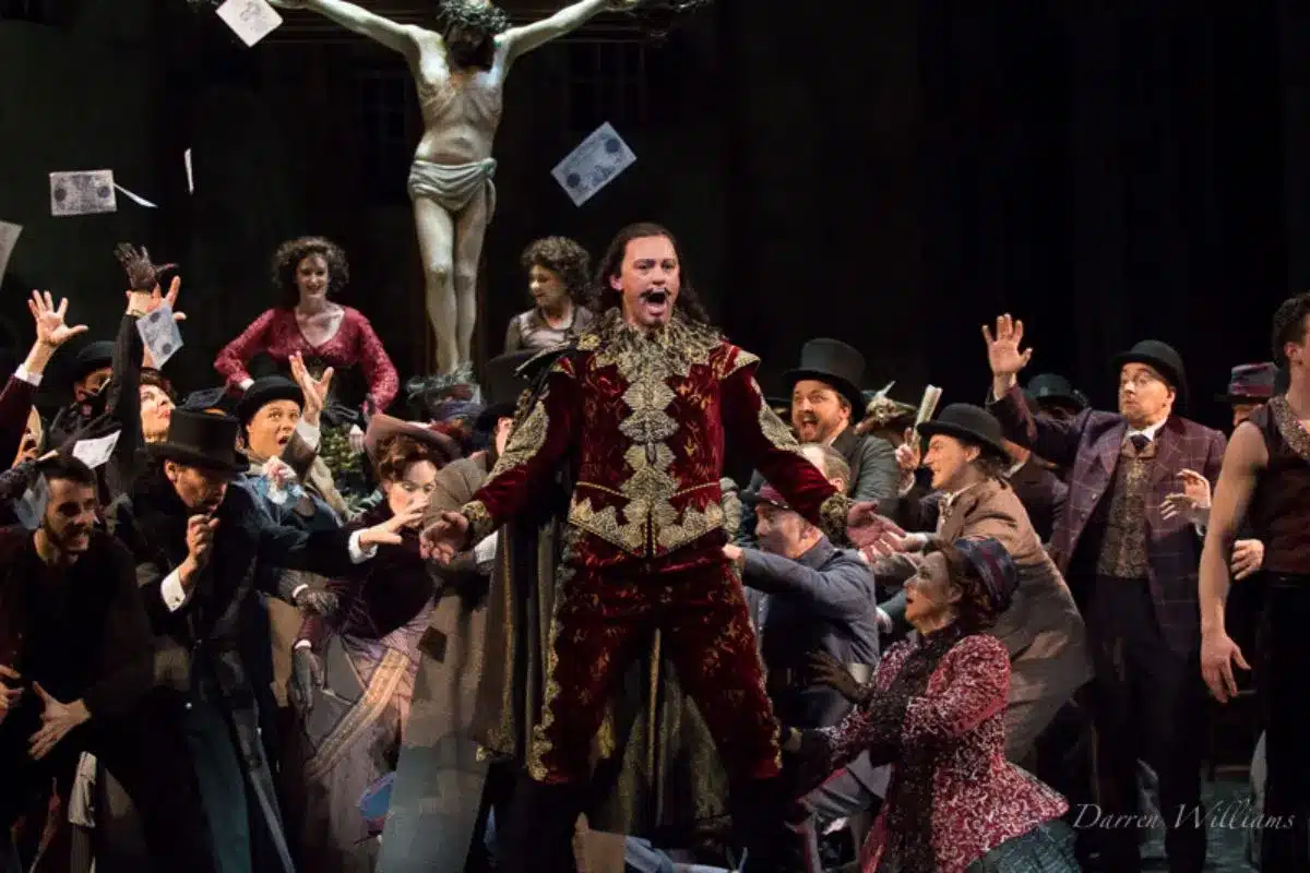 Teddy Tahu Rhodes performs in the title role of Faust, centre stage in elaborate red and gold costume, surrounded by a large ensemble cast. Photo: Darren Williams.