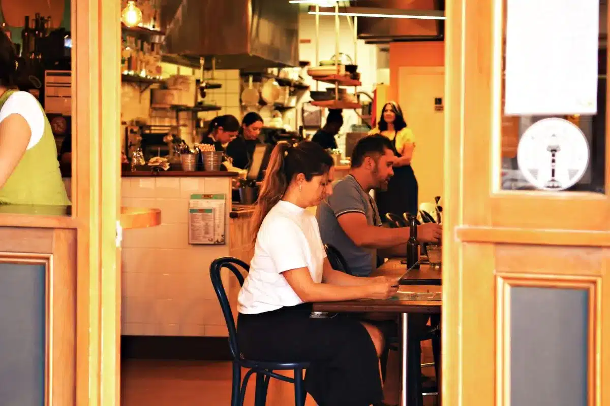 Diners seated at the bar at La Popular Taqueria in Port Adelaide, with the open kitchen busy in the background and Daniella Guevara Muñoz visible among her team