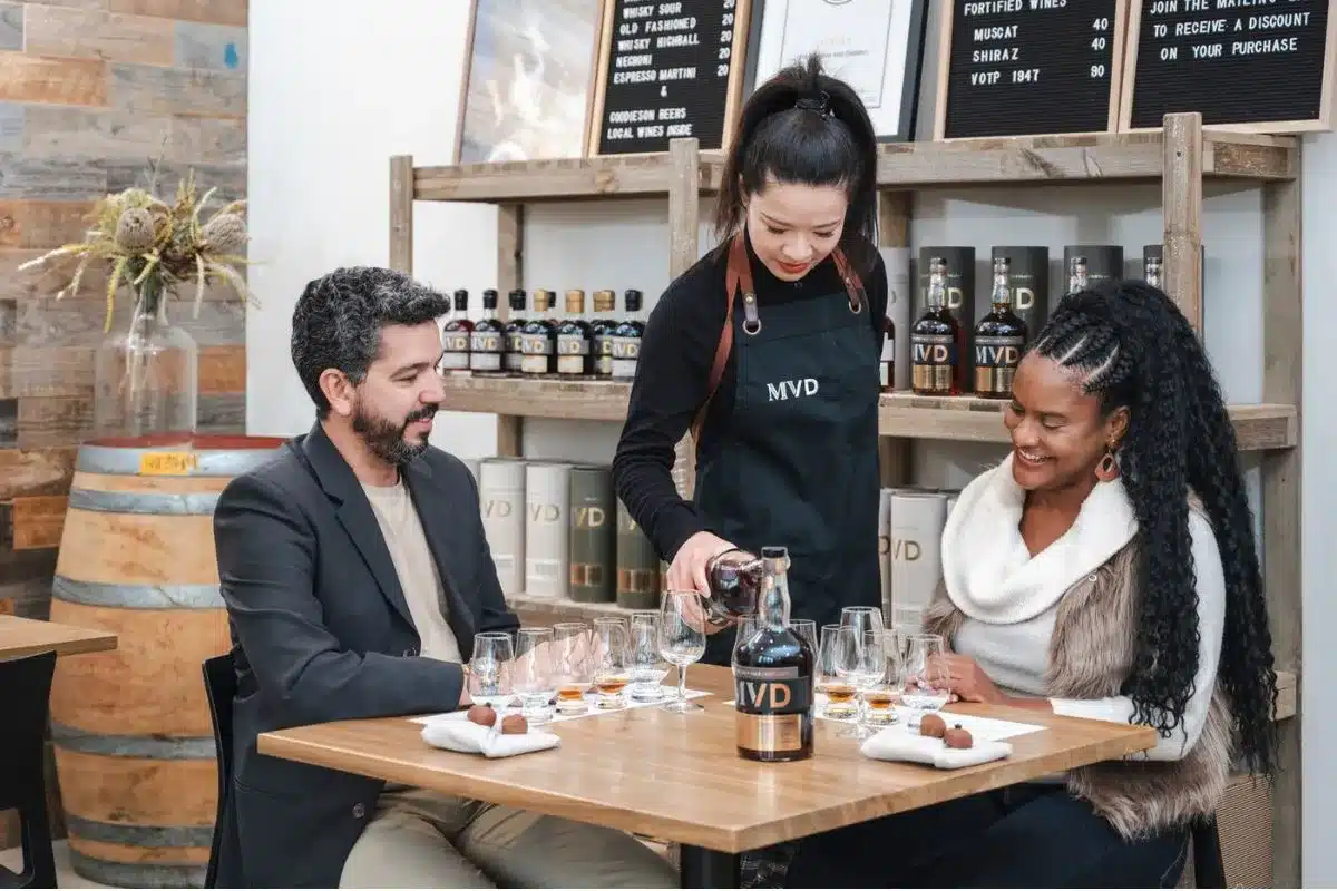 A couple seated in a restaurant being served by a waiter at their table.