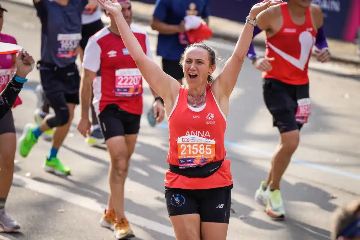 Anna Liptak raises her arms in celebration during the New York City Marathon, wearing her race bib number 21585