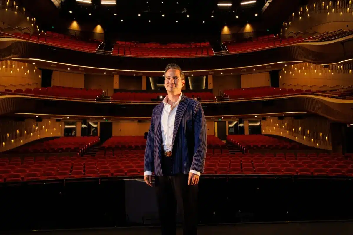State Opera South Australia artistic director Dane Lam stands on stage at the Adelaide Festival Centre, with the empty red-seated auditorium behind him