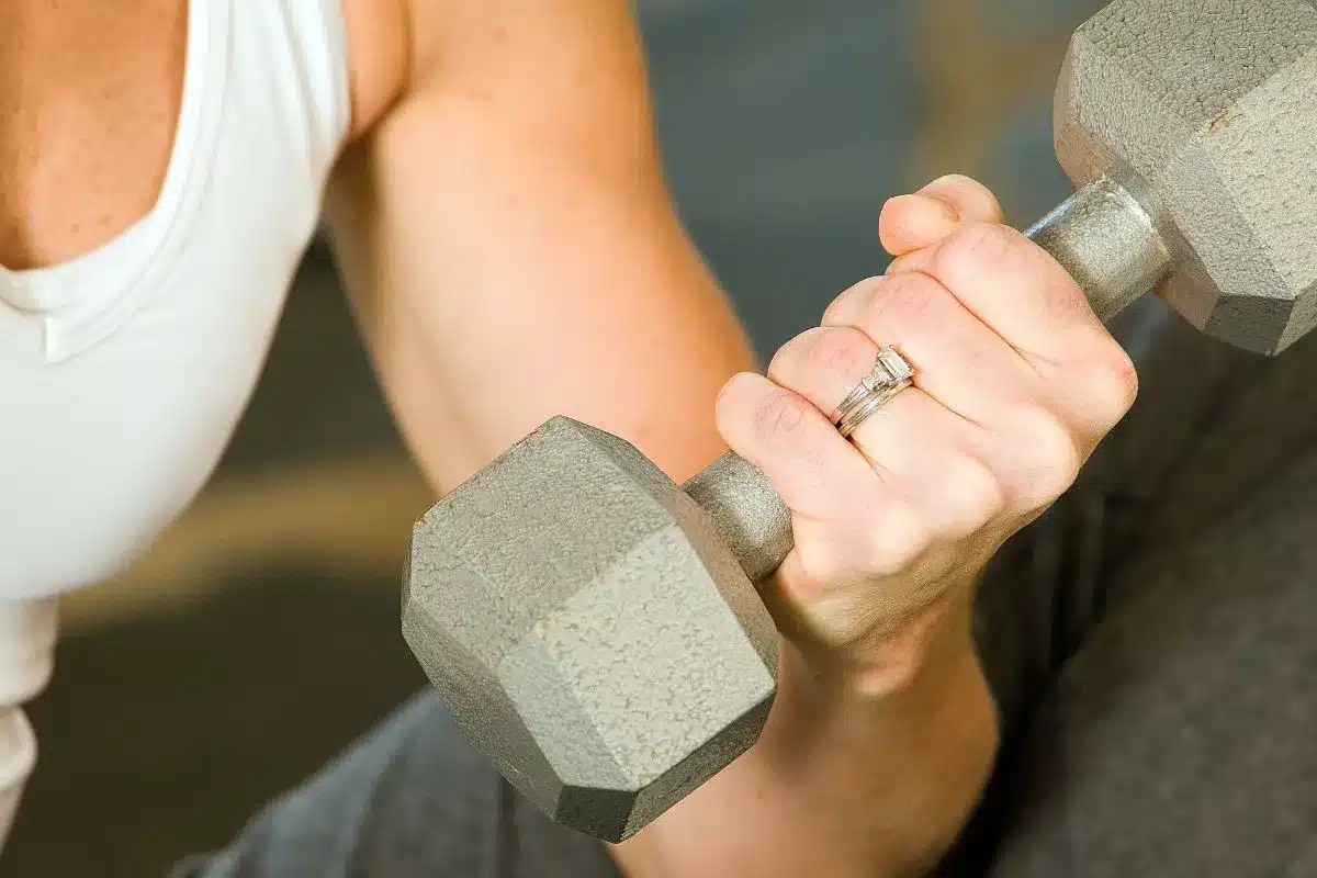 A person holding a hand weight and flexing their bicep.