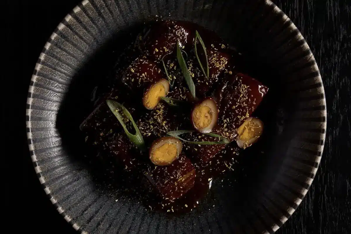 A glazed pork belly and egg dish in a dark ceramic bowl at Huami, SkyCity Adelaide