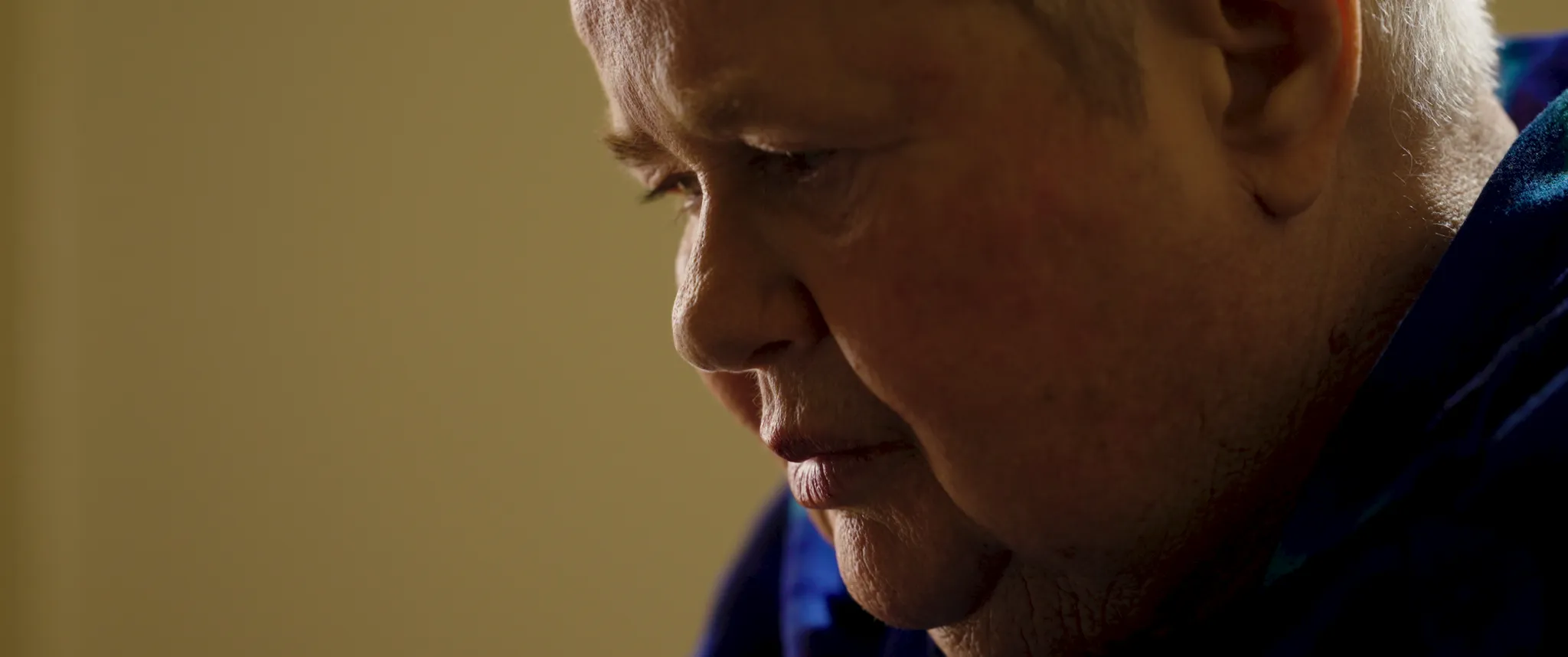 Close-up profile shot of Carolyn, a Minda client featured in A House for Humans, in a reflective moment lit in warm, low light.
