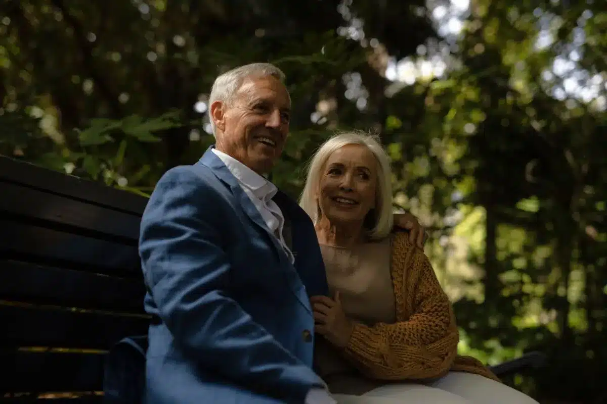 couple sitting together on a park bench surrounded by greenery