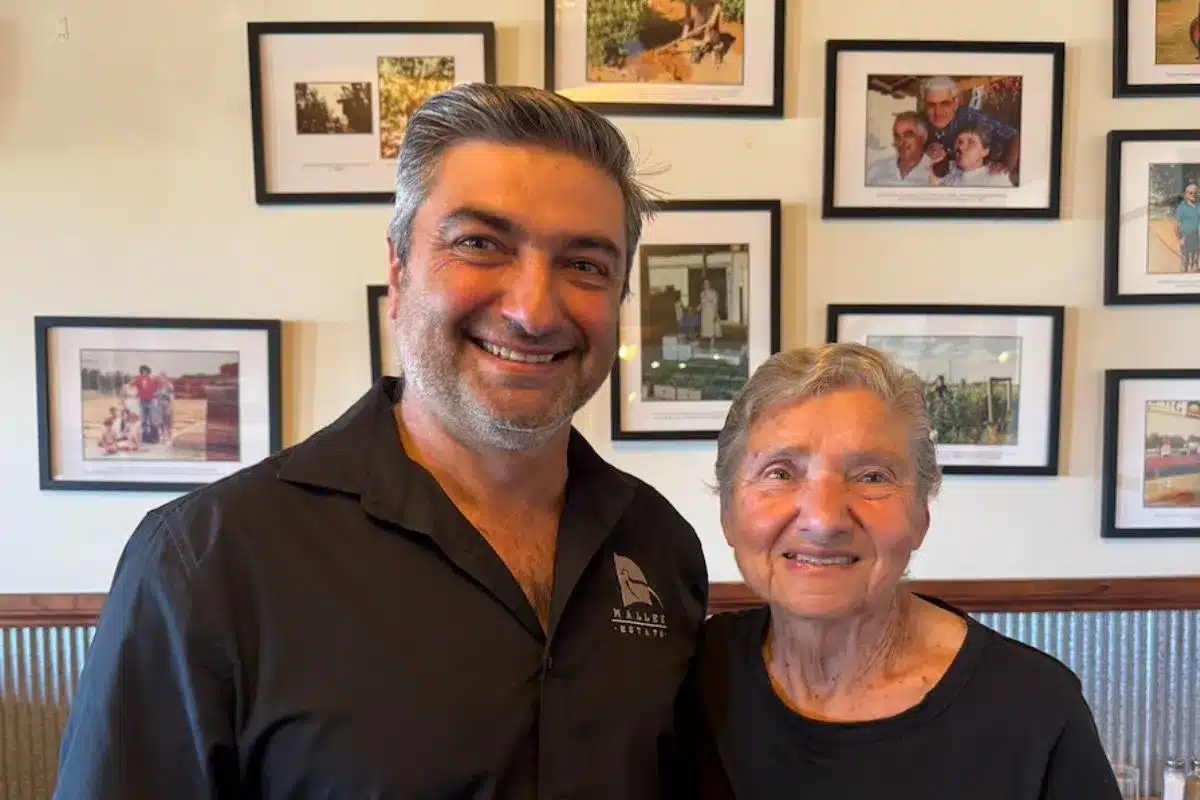 Winemaker Jim Markeas standing with his mother Eleni in front of framed family photographs at Mallee Estate.