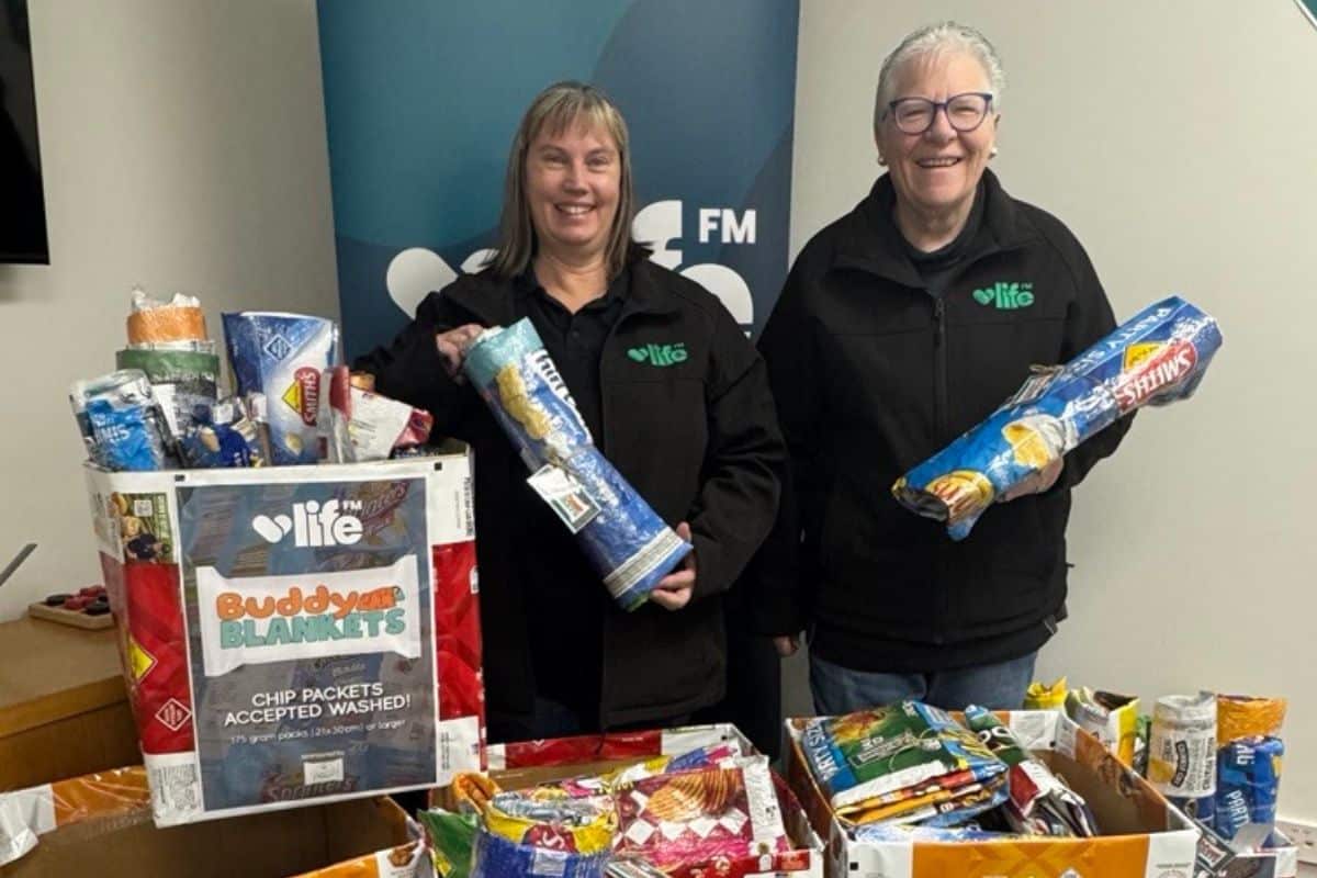 Life FM volunteers with completed Buddy Blankets made from recycled chip packets - two volunteers holding rolled blankets beside a Buddy Blankets donation box