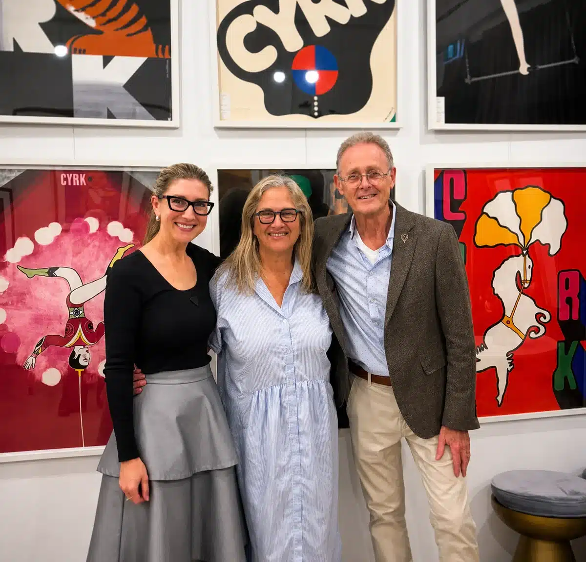 Samantha Knoll with collectors Gina and Sam Rosenberg, standing in front of colourful Polish circus posters at Galeria Grafika.